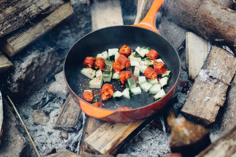 Vegetables cooking in a pan over a wood fire
