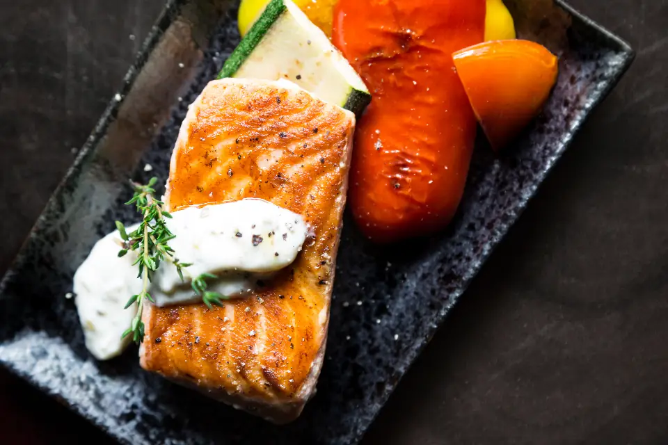 Grilled salmon with roasted peppers on a dark plate